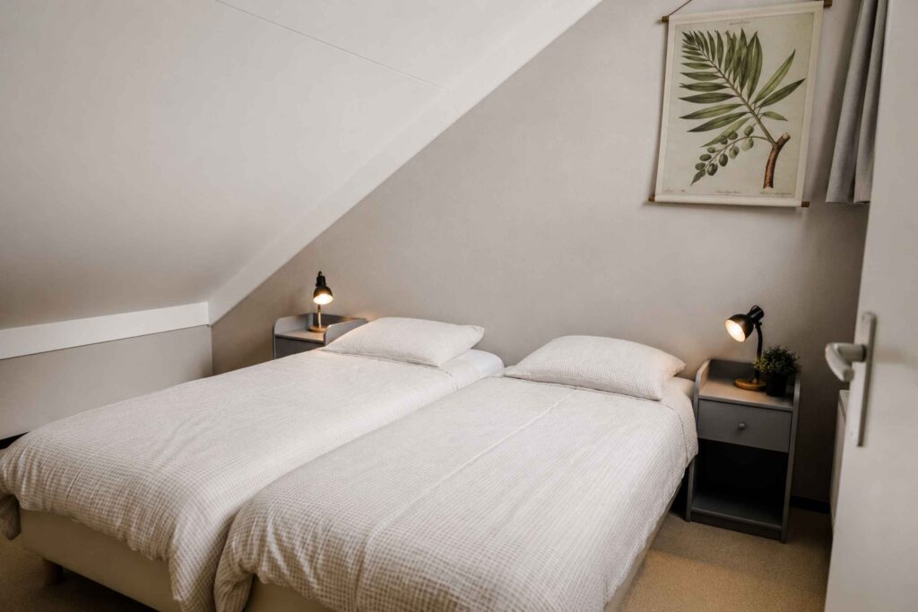 Slaapkamer met twee eenpersoonsbedden onder het schuine dak